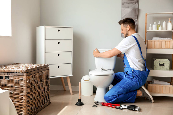Plumber installing toilet in restroom - Zdjęcie, obraz