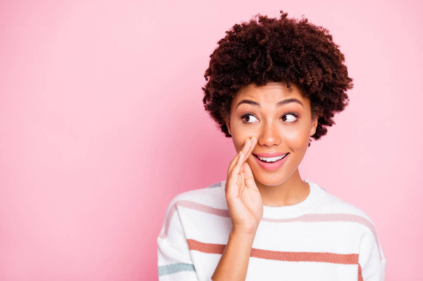 Photo of cheerful charming cute nice black millennial whispering you new information staring at empty space smiling toothily wearing striped white sweater isolated pink pastel color background - Photo, image