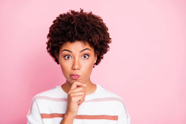 Photo of amazed misunderstanding cute funny black woman touching her chin lost deeply in thoughts wearing white striped sweated isolated over pink pastel color background - Photo, Image