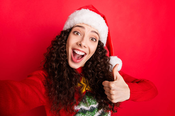 Self-portrait of her she nice attractive lovely charming excited cheerful cheery wavy-haired Santa girl sowing thumbup ad advert isolated on bright vivid shine vibrant red color background - Φωτογραφία, εικόνα