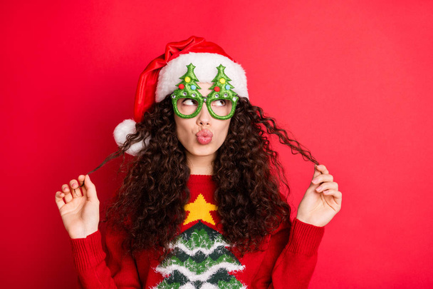 Close-up portrait of her she nice-looking attractive lovely pretty cheerful flirty wavy-haired Santa girl pouted lips playing with curls isolated over bright vivid shine vibrant red color background - Φωτογραφία, εικόνα