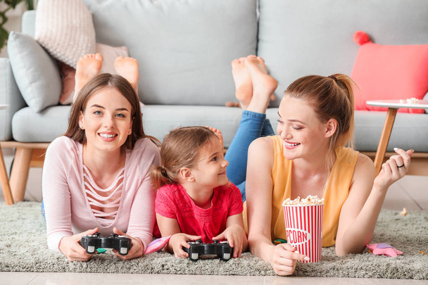 Happy lesbian couple with little daughter playing video game at home - Foto, imagen