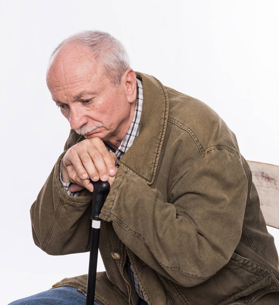 Грустный одинокий пожилой человек с тростью, сидящий на стуле
 - Фото, изображение