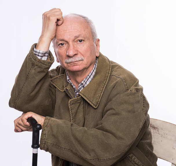 Грустный одинокий пожилой человек с тростью, сидящий на стуле
 - Фото, изображение