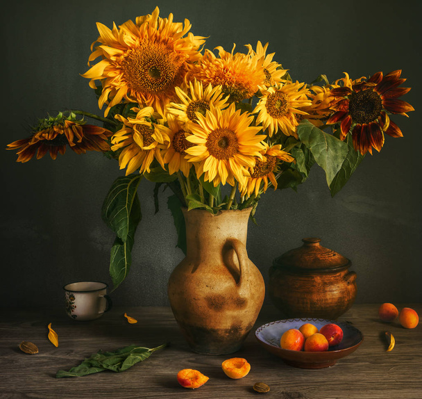Still life with a flower of a sunflower and apricots. Beautiful bouquet of sunflowers. Ripe and tasty apricots. Vintage. Retro. - Photo, Image
