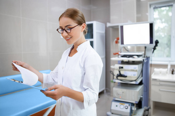Joyful physician looking at clipboard in office stock photo - Photo, image