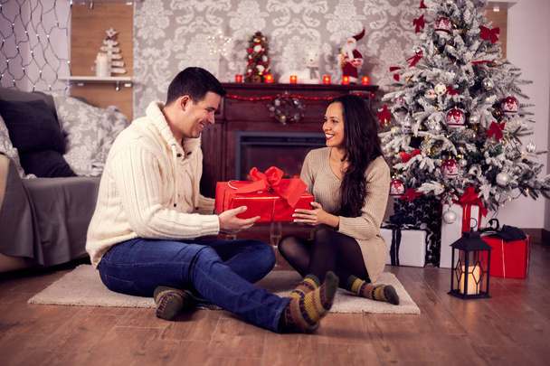 Bella giovane coppia seduta sul pavimento a festeggiare il Natale
 - Foto, immagini