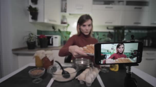 vlog of a housewife, female fashion blogger in kitchen writes video recipe on smartphone for her subscribers, focus on phone - Materiaali, video