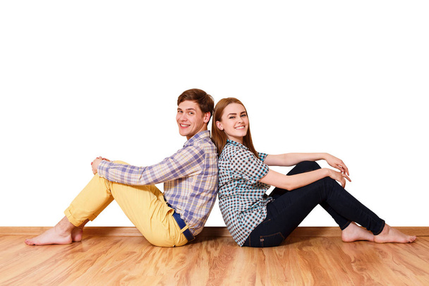 Молодая счастливая пара сидит на паркетном полу
. - Фото, изображение