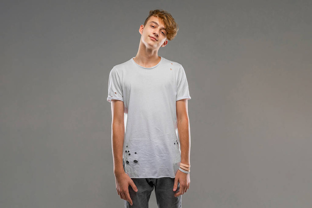 handsome emotional teenager posing in studio against gray  - Foto, imagen