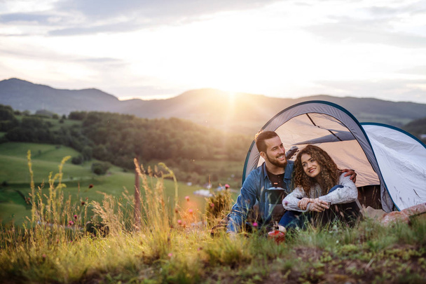 Giovani turisti coppia viaggiatori con tenda riparo seduto nella natura, bere caffè
. - Foto, immagini