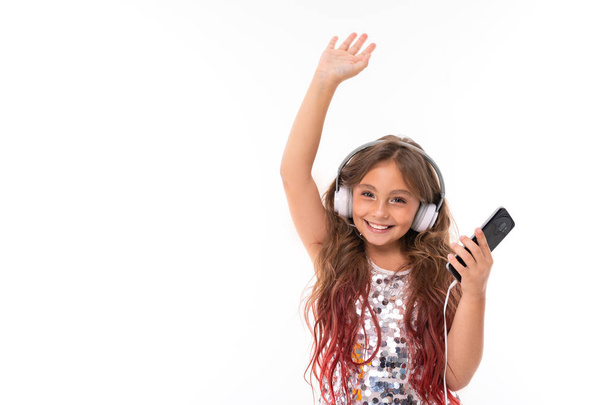 menina bonita posando com fones de ouvido e telefone celular contra fundo branco
 - Foto, Imagem