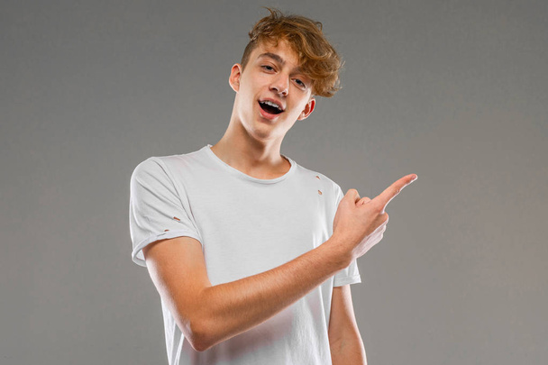 handsome emotional teenager posing in studio against gray  - Zdjęcie, obraz
