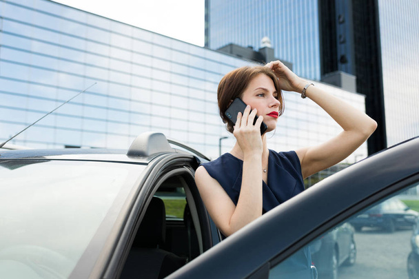 mooie vrouw praten aan de telefoon in de buurt van auto  - Foto, afbeelding