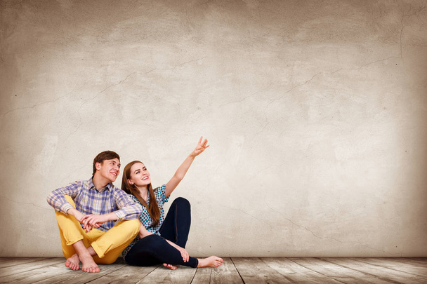 Young happy couple sitting on the parquet floor. - Photo, Image