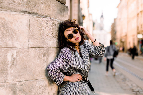 Happy Caucasian woman in summer sun glasses smiling while posing outdoors in the city at sunny day, female person standing with composition copy space on a side - Zdjęcie, obraz