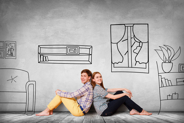 Happy couple sitting on the floor among painted furniture on the wall. - Photo, Image