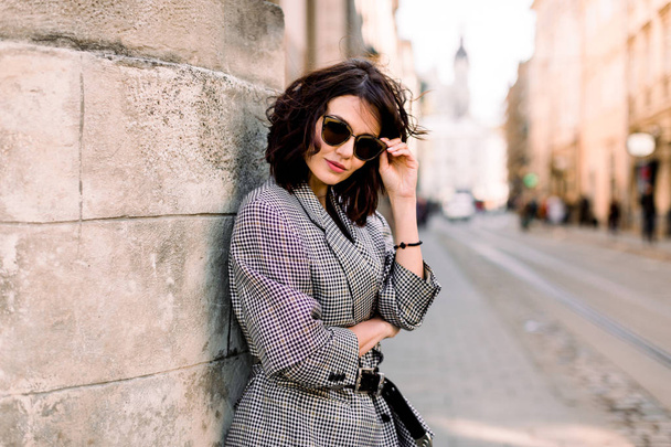 Attractive fashion modern woman in sunglasses standing on the city street. Summer portrait of happy girl on a walk - Foto, Bild
