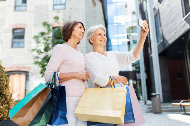old women with shopping bags taking selfie in city - Foto, immagini