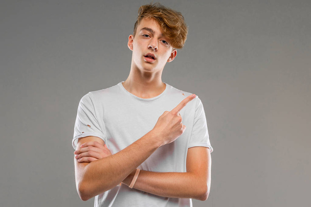 handsome emotional teenager posing in studio against gray  - 写真・画像