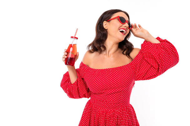 Woman in red dress posing with beverage against white background  - Foto, Imagem