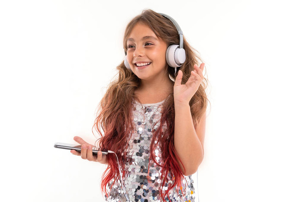 gyönyörű lány pózol fejhallgatóval és mobiltelefon ellen fehér háttér - Fotó, kép