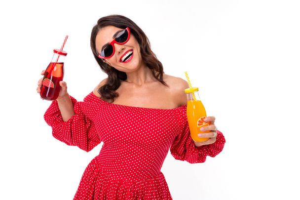 Donna in abito rosso in posa con bevanda contro sfondo bianco
  - Foto, immagini