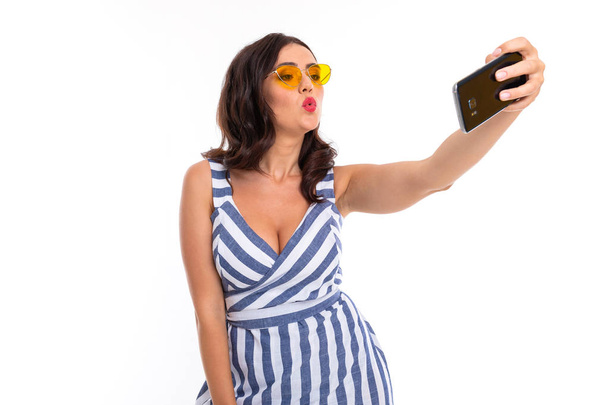 fiatal nő használ telefon visel napszemüveg és csíkos ruha - Fotó, kép