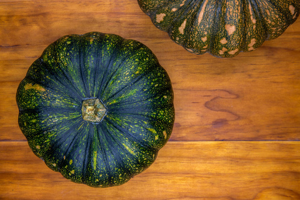 Green pumpkin top view photo on wooden background. Autumn garden harvest concept. Thanksgiving or halloween background - Foto, imagen