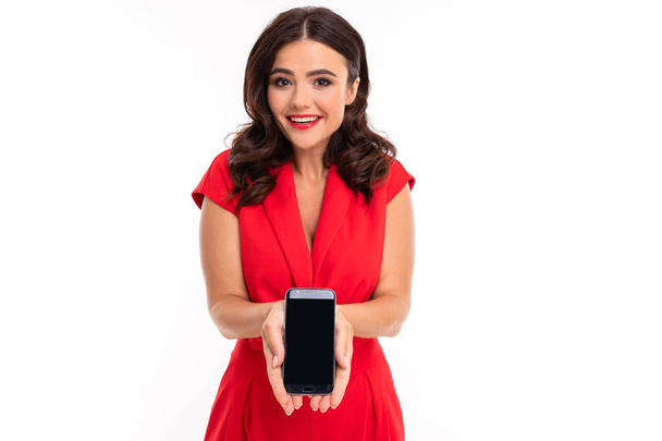 Mujer en vestido rojo posando con teléfono móvil sobre fondo blanco
  - Foto, Imagen