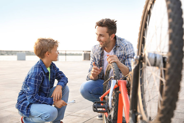 Ojciec i jego syn naprawiający rower na zewnątrz - Zdjęcie, obraz