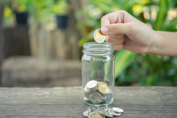 Geschäftsleute stecken die Münze in ein Glasgefäß, um Geld zu sparen. - Foto, Bild