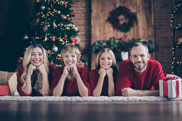 Noel zamanı. Baba anne kardeş kardeş harcama x-mas eve birlikte uyum içinde çelenk yeni yıl ağacı kapalı kırmızı örme kazak giymek yakın zemin yalan - Fotoğraf, Görsel