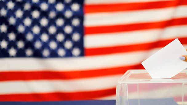 seçim günü oy pusulasını koyan kadın. ABD bayrağı arka plan üzerinde beyaz oy kağıt ile el kapatın. - Fotoğraf, Görsel