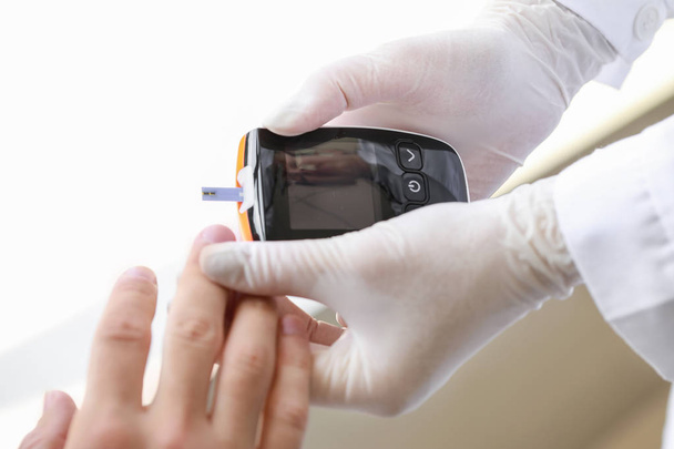 Ο γιατρός ελέγχει το επίπεδο του σακχάρου στο αίμα του διαβητικού ασθενούς στην κλινική, κοντινό - Φωτογραφία, εικόνα