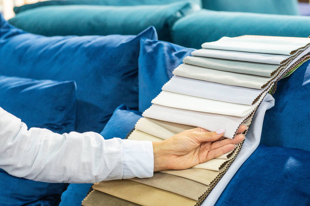 Una giovane donna guarda campioni di tessuto. Seleziona il colore del divano
.  - Foto, immagini