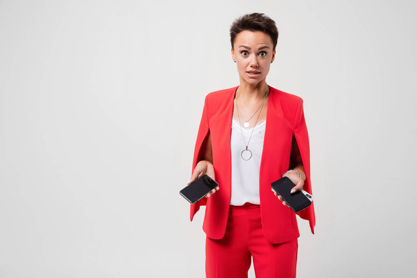 Bizneswoman w czerwonym garniturze pozowanie z telefonów komórkowych na białym tle  - Zdjęcie, obraz