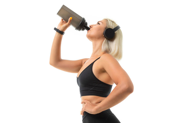 junge schöne blonde Sportlerin mit Kopfhörer und Wasserflasche - Foto, Bild