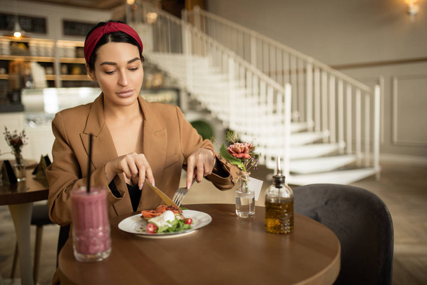 mujer de moda en el bar en la mesa almorzando. Comer alimentos y beber un cóctel
 - Foto, Imagen