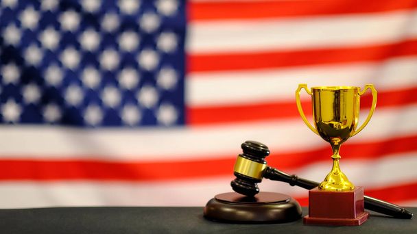 Judges gavel and trophy USA flag. Symbol for jurisdiction. Law concept a wooden judges gavel on table in a courtroom or law enforcement office - Foto, afbeelding