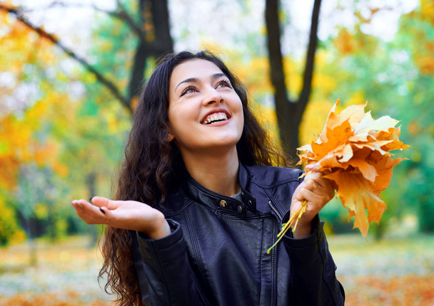 γυναίκα που ποζάρει με τα φύλλα του φθινοπώρου στο πάρκο της πόλης, εξωτερική πορτρέτο - Φωτογραφία, εικόνα