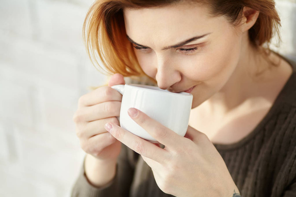 portrait of young attractive smiling woman with a cup of morning coffee or tea. - Fotó, kép