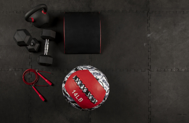Dumbbell, cuerda, гири, cojin y pelota para hacer ejercicios de crossfit y fitness en piso de fondo color negro
 - Фото, изображение