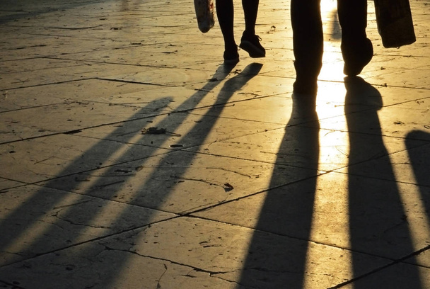 Sombras de piernas en el pavimento al atardecer
 - Foto, Imagen