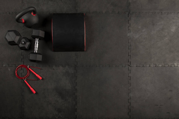 Dumbbell, cuerda, kettlebell y cojin para hacer ejercicios de crossfit y fitness en piso de fondo color negro - Fotoğraf, Görsel
