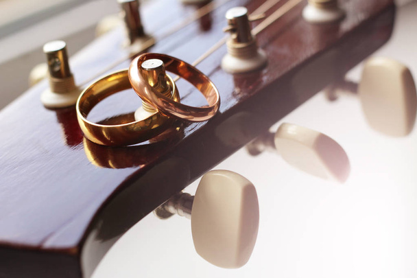 2つの金の結婚指輪は、ギターの弦のクローズアップに横たわっています - 写真・画像