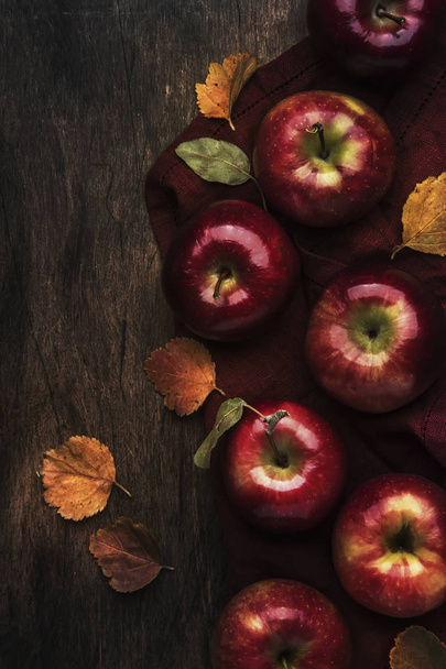 Autumn food background. Ripe apples with fallen leaves on rustic wooden table. Top view. Copy space - Foto, Imagem