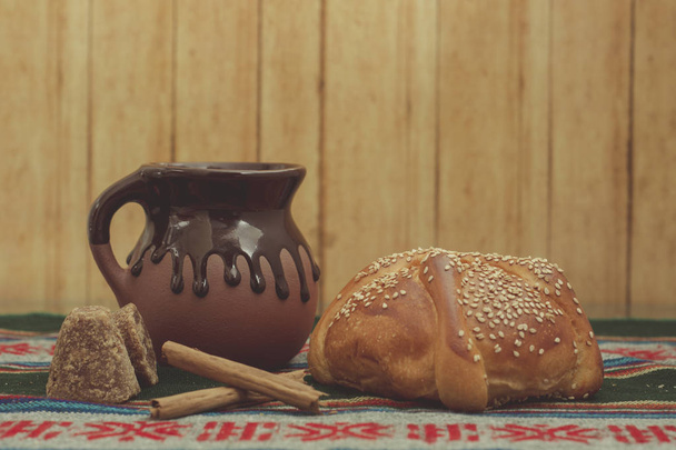 pan de muerto cortado con taza de café, canela y piloncillo en fondo de madera
 - Foto, imagen