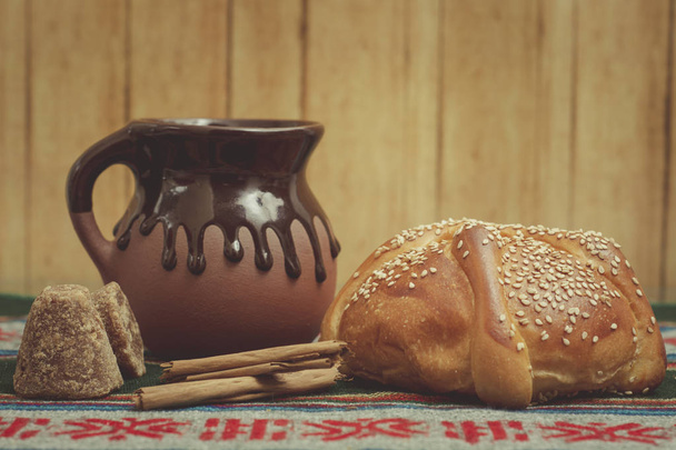 pan de muerto cortado con taza de café, canela y piloncillo en fondo de madera
 - Foto, Imagen