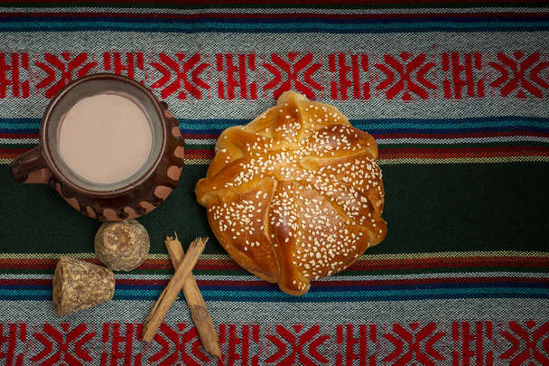 pan de muerto cortado con taza de cafe, canela y piloncillo en fondo de madera Nincs magyar neve - Fotó, kép